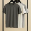 Three premium cotton crew neck t-shirts in charcoal, off-white, and light grey hanging on black hangers.